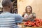 black girl selling tomatoes in a local african market to a customer smiling and feeling happy and satisfied