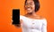 Black Girl Showing Phone Empty Screen Standing, Orange Background, Mockup