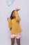 Black girl in yellow shirt playing, photo with white background. child playing with balloon isolated