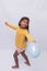 Black girl in yellow shirt playing, photo with white background. child playing with balloon isolated
