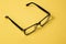 Black glasses with clear lenses. Frame of glasses on a yellow background. Glasses for correcting human vision or working