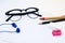 Black glasses, white paper, pencil, pen, pink sharpener, eraser