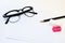 Black glasses, white paper, pencil, pink sharpener and eraser