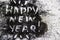 A black glitter on the white background.  Words happy new year painted on the black sand