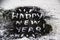 A black glitter on the white background.  Words happy new year painted on the black sand