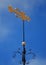 Black and gold stylized fish weather vane against deep blue sky.