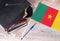 Black graduation hat on books next to Cameroon flag, education concept