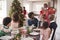 Black grandfather opening champagne for his multi generation family, gathered in the dining room for Christmas dinner