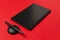 Black graphics tablet, stylus on the red background