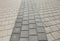 Black and grey cobblestones of a footpath have been laid in a geometrical pattern. They are worn with time