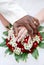 Black groom and white fiance hands on bouquet