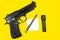 Black gun, reminder note paper, pen and flashlight lies on a yellow background. Private detectives work. Searching information