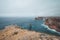 Black-haired adventurer stands at the end of Cape Cabo de Sao Vicente in the southwest of Portugal in the Algarve region. Man is