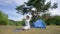 Black-haired hiker practices yoga on mat by camp tent
