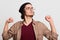 Black haired sleepy calm guy doing stretch, exercising, looking aside, posing  over light grey background, having