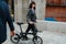 Black-haired woman tugging ebike, walking on the street