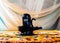 Black handmade Shiva Lingam figure with on an orange altar under curtains