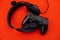 Black headphones and a gamepad on a red background. Cybersport concept