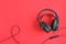 Black headphones on red background. Concept listening to audio material and abstract, distance education. Top view copy space