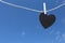 Black Heart hung on hemp rope on blue sky background.