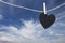 Black Heart hung on hemp rope on blue sky background.