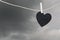 Black Heart paper hanging on a brown hemp rope on rain clouds ba