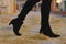 Black heel ankle boots walking on yellow straw