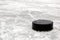 Black hockey puck on ice rink