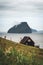 Black house on famous faroese Witches Finger Trail and Koltur island on background. Sandavagur village, Vagar island