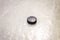 Black ice hocikey rubber puck located on arena ice rink. Ice and puck have small and deep scratches