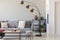 Black industrial lamp next to grey couch with patterned pillows, coffee table and pouf in monochromatic living room