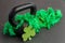 Black iron kettlebell with green feather boa on a black gym floor, holiday fitness, green shamrock