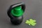 Black iron kettlebell with green leprechaun hat on a black gym floor, holiday fitness, green shamrock