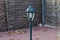 Black iron pillar with a lantern on a brown sidewalk
