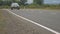 A black jeep goes on the road, shooting a new road surface in the countryside on which the car passes, in the background