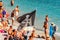 Black Jolly Roger pirate flag on the beach full of sanbathing and swimming tourists in famous Monterosso Al Mare, Cinque Terre,