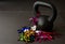 Black kettlebell on a black gym floor with blue, green, red, pink and gold noisemakers