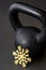 Black kettlebell on a black gym floor with a gold snowflake