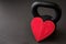 Black kettlebell on a black gym floor with large red heart