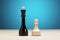 Black king vs white chess pawn piece against blue background. Competition, career or conflict in business