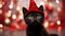 Black kitten in a red wizard\\\'s cap. Kitten celebrates New Year