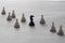 Black knight and white pawns on white background. Plastic chess items from travel set. Selective focus