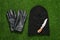 Black knitted balaclava, gloves and knife on green grass, flat lay