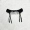 Black lace belt for stockings in female hand. Fashionable concep