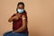 Black lady in face mask pointing at plaster on arm
