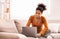 Black Lady Using Laptop Sitting On Sofa At Home