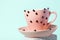 Black ladybugs with small red spots on pink tea cup