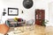 Black lamp above armchair and table in bright living room interior with poster and plants. Real photo