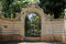 Black large retro gate made of iron bars with a forged pattern on a concrete dirty brown fence