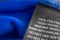 Black laundry care washing instructions clothes label on blue jersey polyester sport shirt